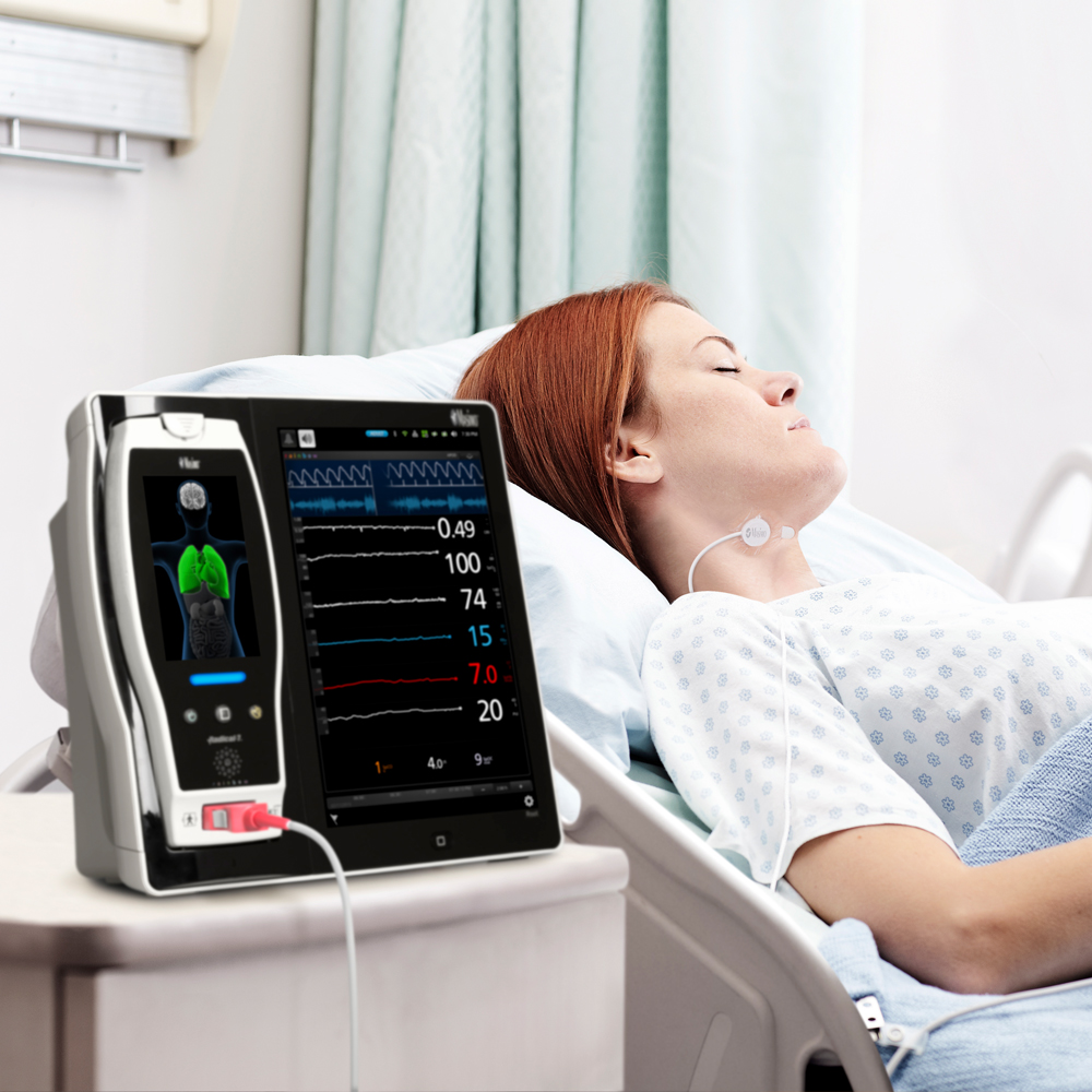 Patient in hospital bed monitored by Masimo Root device.